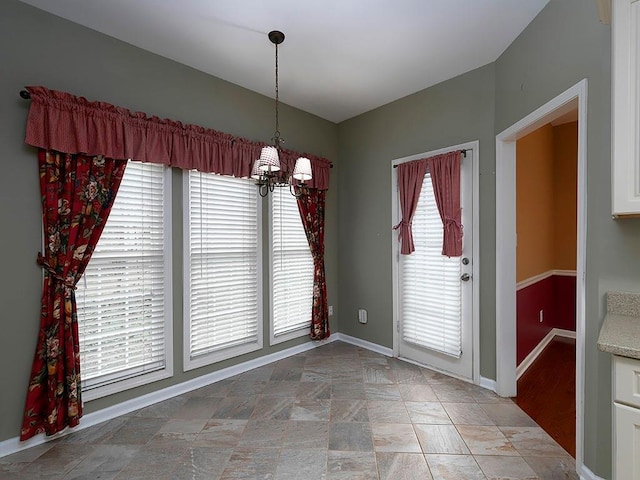 unfurnished dining area with an inviting chandelier and baseboards