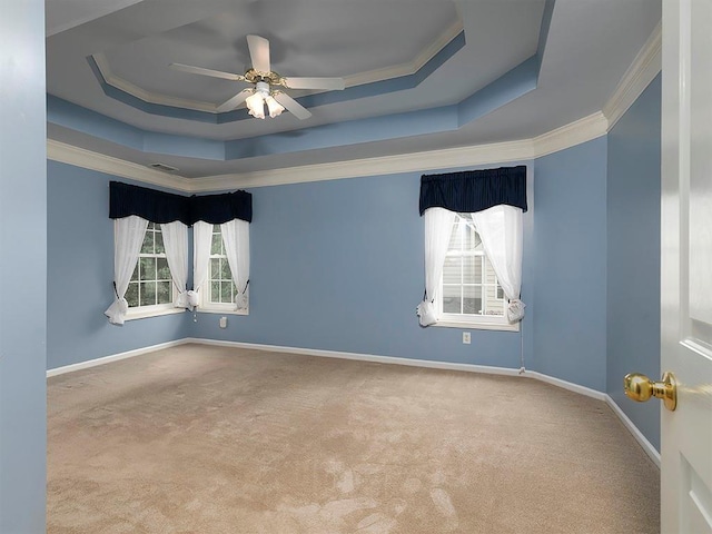 carpeted empty room featuring ornamental molding, a ceiling fan, and a tray ceiling