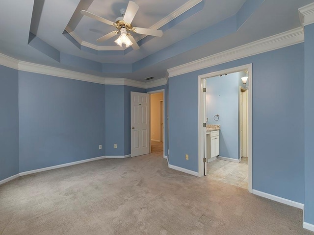 unfurnished bedroom with baseboards, ornamental molding, light colored carpet, and a tray ceiling