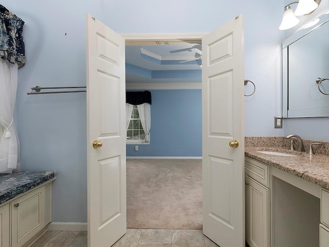 bathroom with ornamental molding, baseboards, vanity, and a tray ceiling