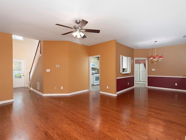 unfurnished living room featuring wood finished floors, stairs, ceiling fan with notable chandelier, baseboards, and visible vents