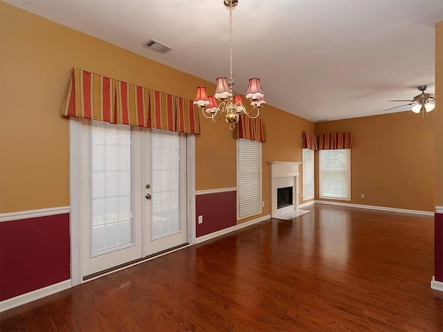 unfurnished living room featuring visible vents, baseboards, a high end fireplace, wood finished floors, and ceiling fan with notable chandelier