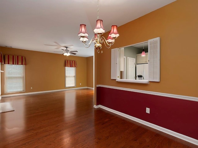 empty room featuring baseboards, wood finished floors, and ceiling fan with notable chandelier