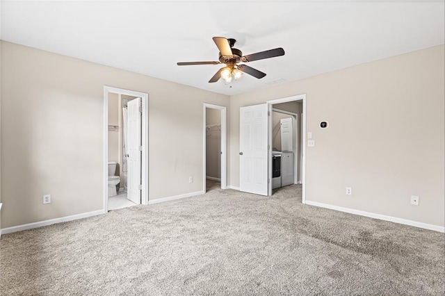 unfurnished bedroom featuring ensuite bath, light colored carpet, ceiling fan, a spacious closet, and a closet