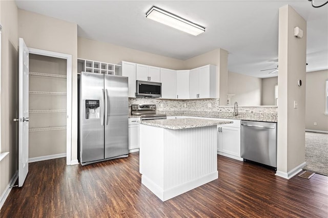 kitchen featuring white cabinetry, ceiling fan, stainless steel appliances, light stone counters, and dark hardwood / wood-style flooring