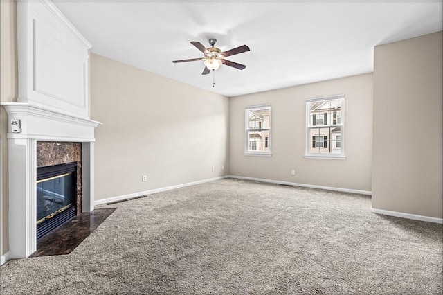 unfurnished living room featuring dark colored carpet, ceiling fan, and a high end fireplace