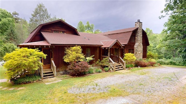 log cabin featuring a gambrel roof, driveway, roof with shingles, a chimney, and a front yard