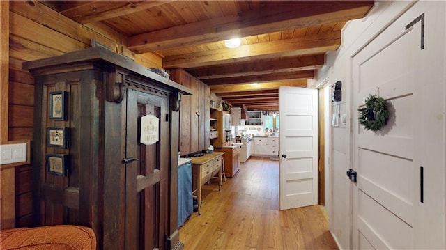 hall with light wood-style floors, wood ceiling, beamed ceiling, and wood walls