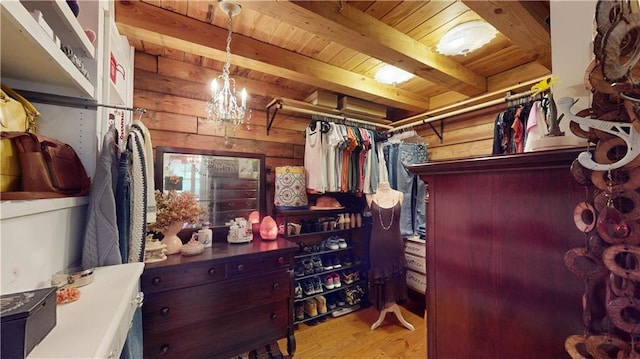 spacious closet featuring a notable chandelier, beamed ceiling, and wood finished floors