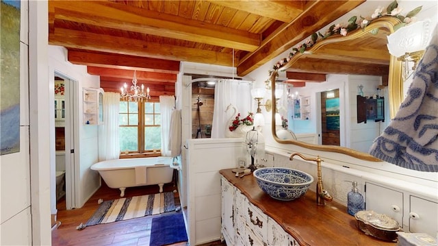 full bath featuring a stall shower, beam ceiling, a sink, and an inviting chandelier