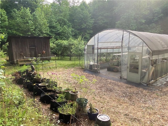 view of yard featuring a vegetable garden, fence, a greenhouse, and an outdoor structure