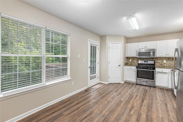 7420 Bristol Cir, Douglasville, GA 30134 - kitchen with appliances with stainless steel finishes, dark wood-style flooring, white cabinetry, tasteful backsplash, and a textured ceiling