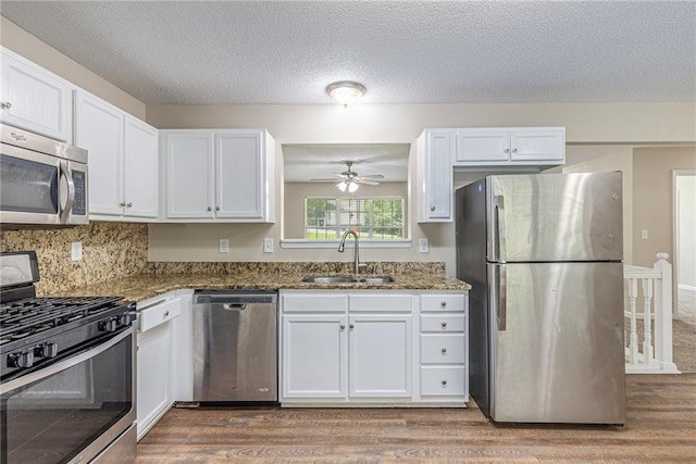 7420 Bristol Cir, Douglasville, GA 30134 - kitchen with appliances with stainless steel finishes, wood finished floors, white cabinets, dark stone counters, and a textured ceiling