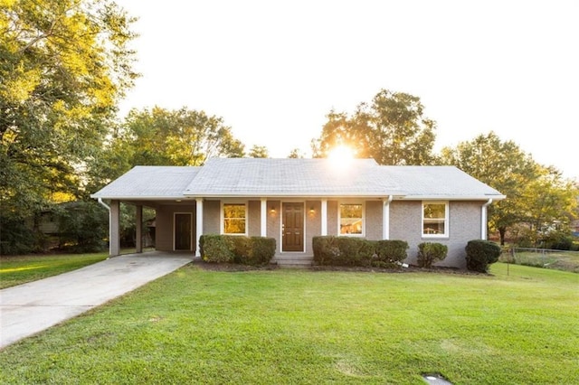 ranch-style home with concrete driveway, a front lawn, and an attached carport