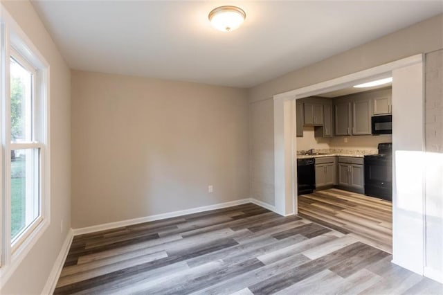 kitchen with a wealth of natural light, gray cabinets, black appliances, and wood finished floors