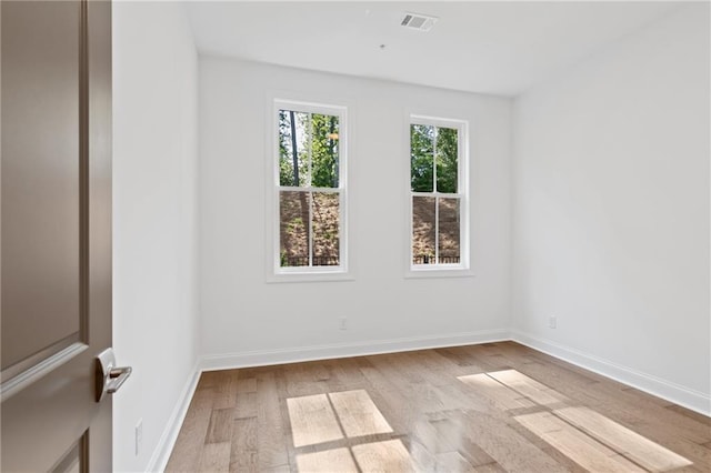 unfurnished room featuring wood finished floors, visible vents, and baseboards