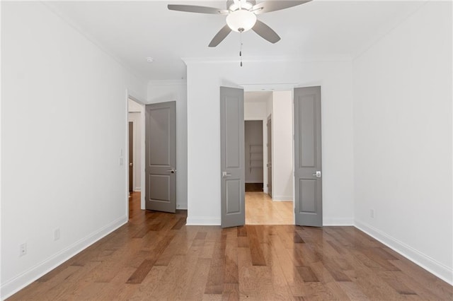 unfurnished bedroom featuring light wood finished floors, a ceiling fan, baseboards, and crown molding