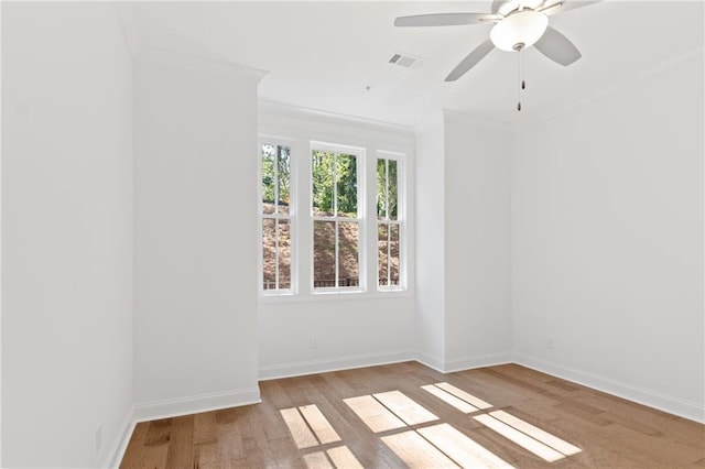 spare room with visible vents, baseboards, ceiling fan, wood finished floors, and crown molding