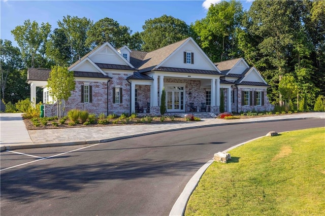 craftsman inspired home featuring french doors, brick siding, a front yard, a standing seam roof, and metal roof