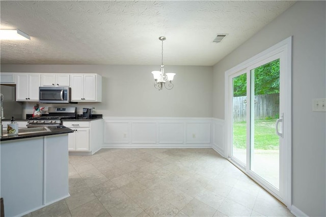 5279 Leecroft Dr, Buford, GA 30518 - kitchen with appliances with stainless steel finishes, dark countertops, white cabinetry, a chandelier, and decorative light fixtures
