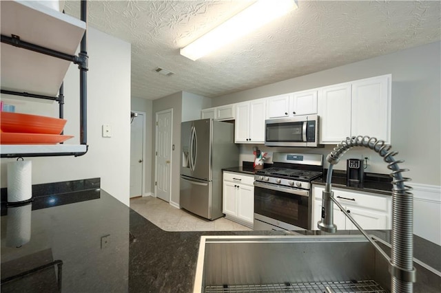5279 Leecroft Dr, Buford, GA 30518 - kitchen featuring stainless steel appliances, dark countertops, white cabinets, and a textured ceiling