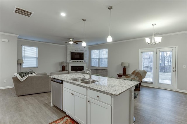 kitchen featuring dishwasher, white cabinetry, sink, a large fireplace, and an island with sink