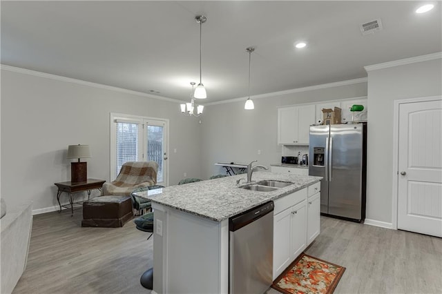 kitchen featuring pendant lighting, sink, stainless steel appliances, white cabinets, and a center island with sink