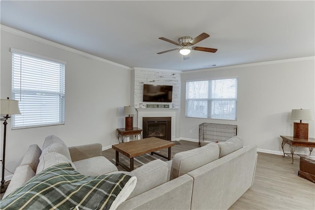 living room featuring ornamental molding, ceiling fan, a fireplace, and light hardwood / wood-style floors