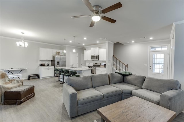 living room with ornamental molding, ceiling fan with notable chandelier, and light wood-type flooring