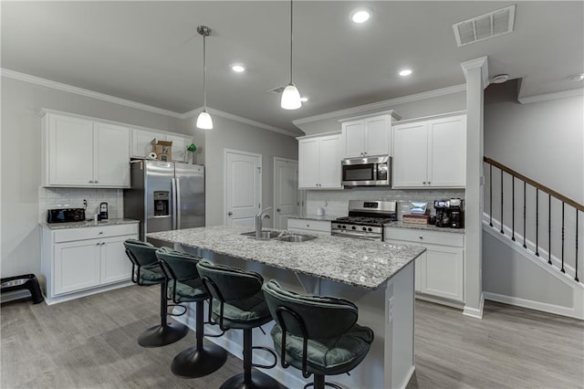 kitchen with decorative light fixtures, stainless steel appliances, and white cabinets