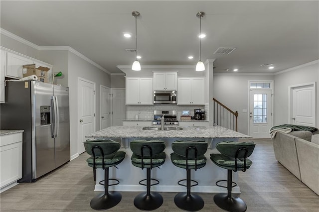 kitchen featuring appliances with stainless steel finishes, pendant lighting, white cabinets, and light stone counters