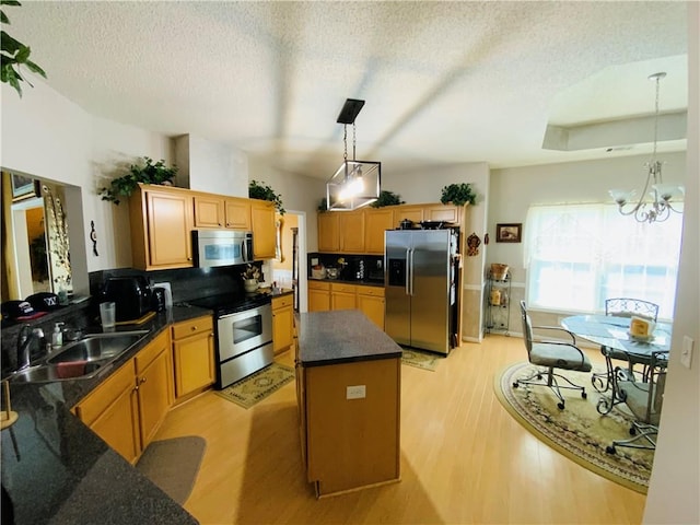 kitchen with appliances with stainless steel finishes, a center island, sink, and light hardwood / wood-style flooring