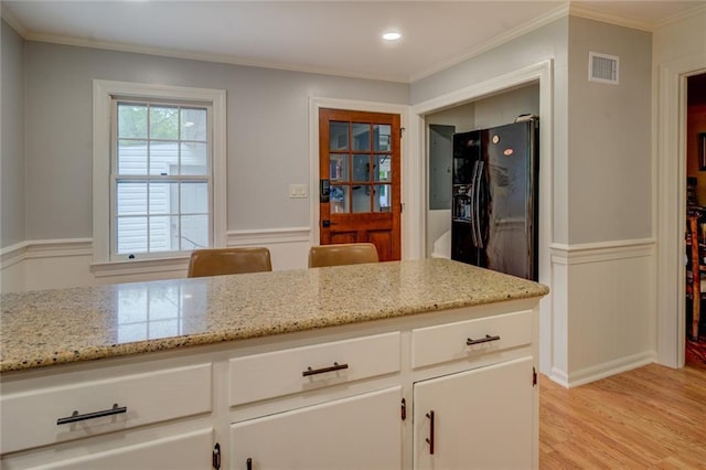 500 Cochran Rd, Covington, GA 30014 - kitchen featuring black refrigerator with ice dispenser, wainscoting, light wood-style flooring, white cabinets, and light stone countertops