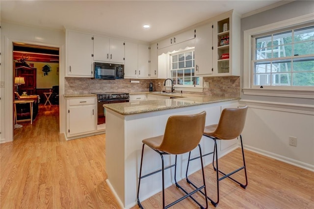 500 Cochran Rd, Covington, GA 30014 - kitchen featuring black appliances, a sink, white cabinetry, a kitchen bar, and decorative backsplash