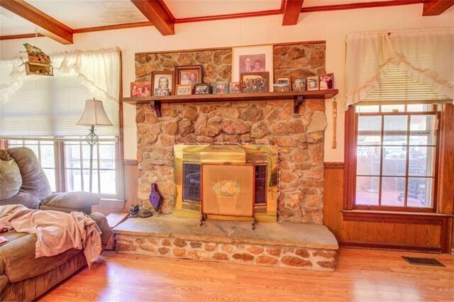 living room featuring beamed ceiling, hardwood / wood-style floors, and a stone fireplace