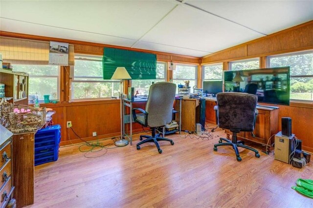 office space with lofted ceiling, wooden walls, and light wood-type flooring