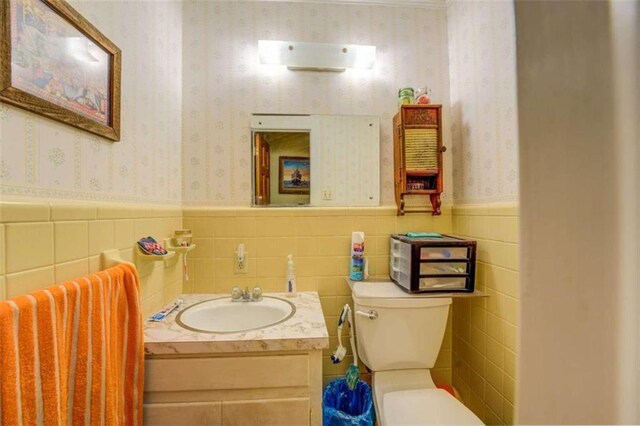 bathroom featuring backsplash, tile walls, toilet, and vanity