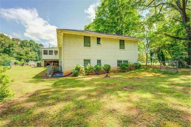 view of home's exterior featuring a yard, brick siding, and fence