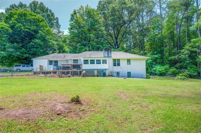 rear view of house featuring a lawn, a wooden deck, and fence