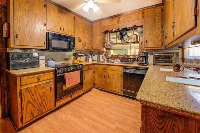 kitchen featuring a toaster, a sink, light wood-type flooring, light stone countertops, and black appliances