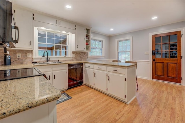 500 Cochran Rd, Covington, GA 30014 - kitchen featuring black appliances, a sink, a peninsula, light wood finished floors, and white cabinetry