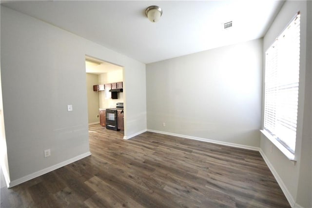 spare room with a wealth of natural light and dark hardwood / wood-style floors