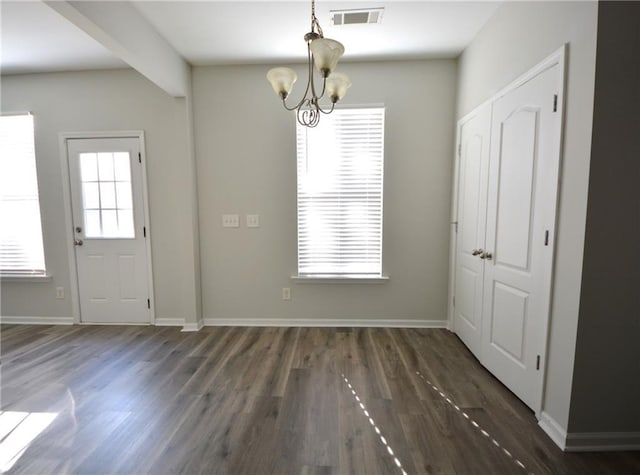 unfurnished dining area featuring a notable chandelier and dark hardwood / wood-style flooring