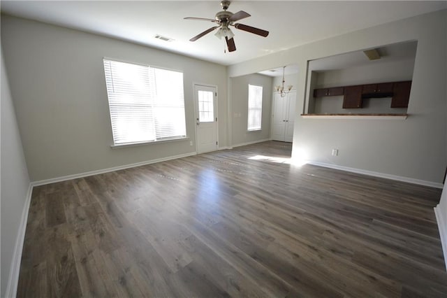 spare room with ceiling fan with notable chandelier and dark wood-type flooring