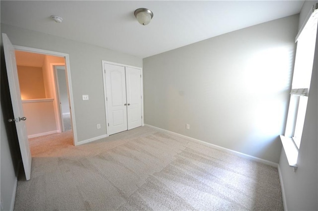 unfurnished bedroom with light colored carpet and a closet