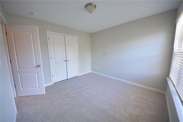 unfurnished bedroom featuring light colored carpet and a closet