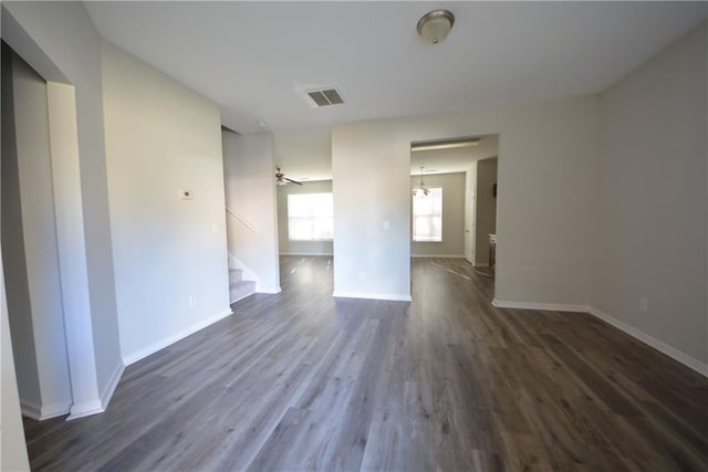 unfurnished room with ceiling fan with notable chandelier and dark hardwood / wood-style floors