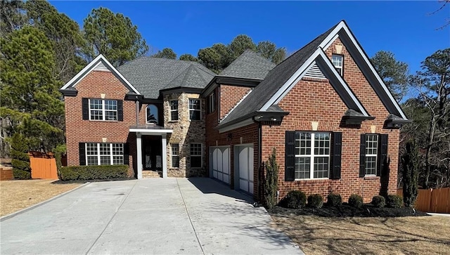 traditional-style home with brick siding, fence, a garage, stone siding, and driveway