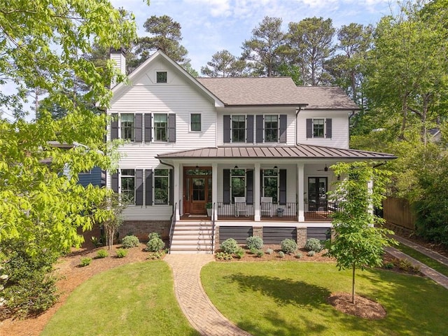 modern farmhouse with a shingled roof, a front lawn, a chimney, a standing seam roof, and covered porch