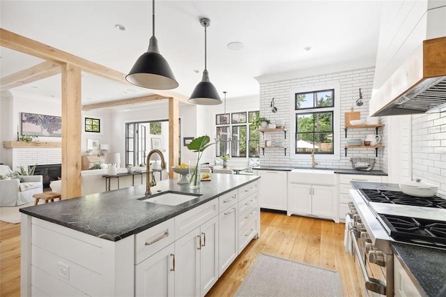 kitchen with high end range, open shelves, a sink, and wall chimney exhaust hood